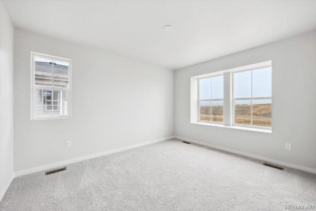 carpeted spare room with baseboards and visible vents
