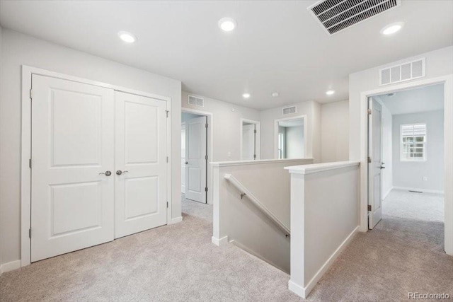 corridor featuring carpet floors, an upstairs landing, and visible vents