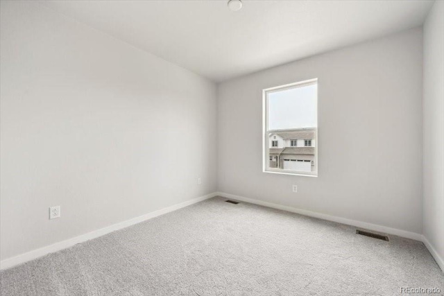 spare room featuring baseboards, visible vents, and carpet