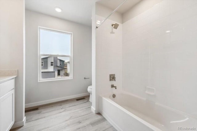full bath featuring toilet, wood finished floors, baseboards, vanity, and shower / bathtub combination