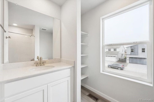 bathroom with visible vents, wood finished floors, vanity, and a shower