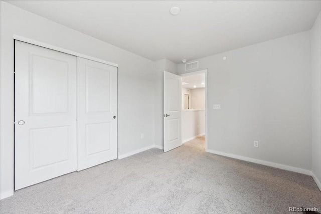 unfurnished bedroom featuring carpet floors, baseboards, visible vents, and a closet