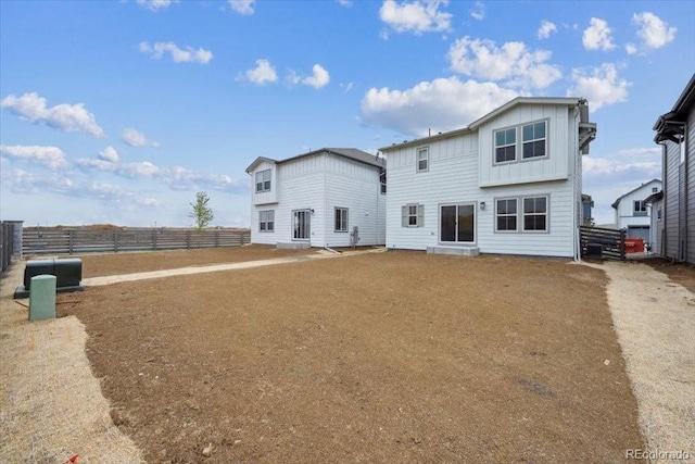 back of property featuring board and batten siding and fence
