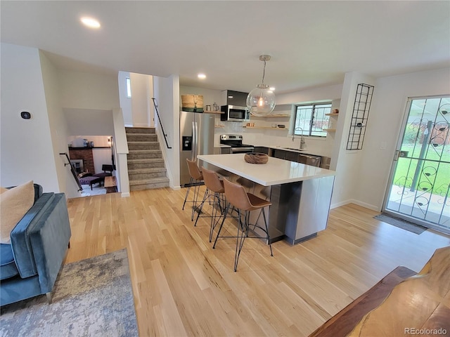 315 E 112th Dr, Northglenn, CO 80233 - kitchen with appliances with stainless steel finishes, light wood finished floors, a breakfast bar, light countertops, and baseboards