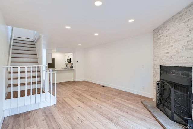 8197 S Fillmore Way, Centennial, CO 80122 - unfurnished living room featuring light wood-style floors, stairway, baseboards, a fireplace, and recessed lighting