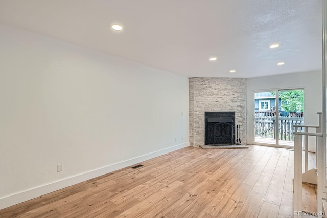 8197 S Fillmore Way, Centennial, CO 80122 - unfurnished living room featuring a stone fireplace, light wood finished floors, baseboards, and recessed lighting