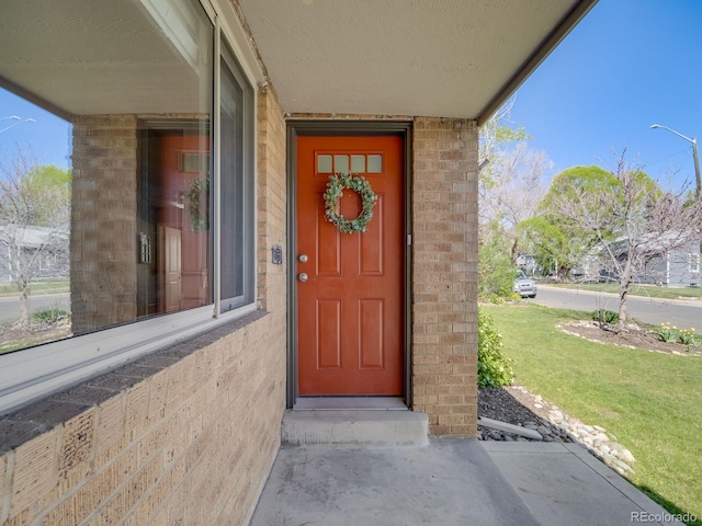 property entrance with brick siding and a yard