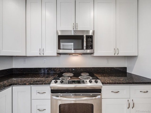 kitchen with white cabinets, stainless steel appliances, and dark stone countertops