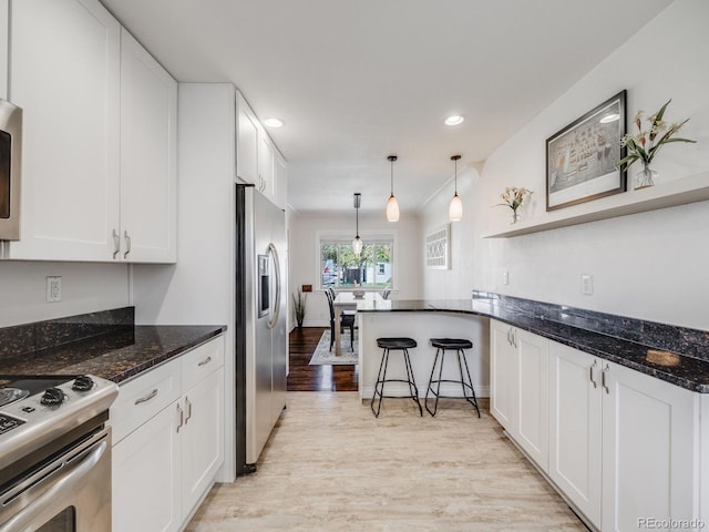 kitchen featuring light wood-type flooring, dark stone counters, white cabinetry, and stainless steel appliances