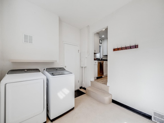 washroom with washing machine and clothes dryer, light colored carpet, laundry area, and visible vents