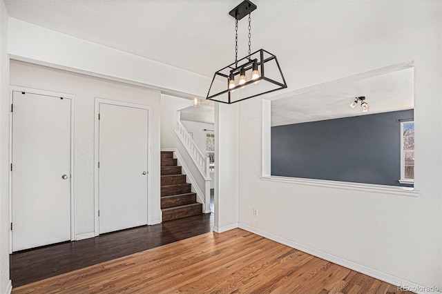 entrance foyer featuring a chandelier, stairs, wood finished floors, and baseboards