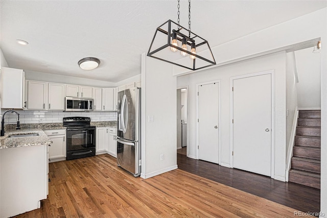 kitchen with appliances with stainless steel finishes, a sink, light stone counters, and tasteful backsplash