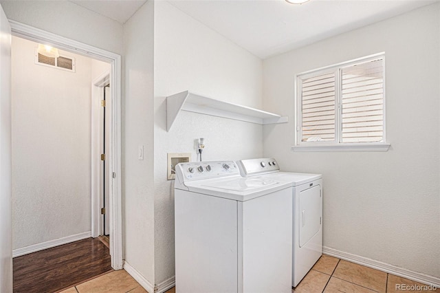 washroom featuring independent washer and dryer, light tile patterned floors, and baseboards