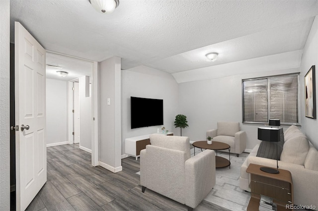 living area featuring wood finished floors, baseboards, and a textured ceiling