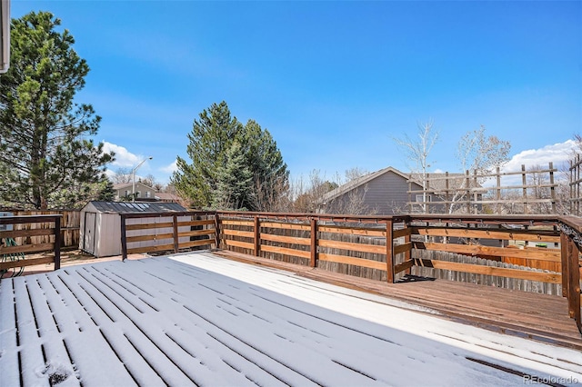 wooden terrace with a storage unit, an outdoor structure, and fence