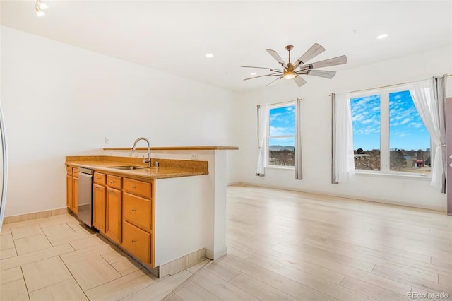 kitchen featuring dishwasher, ceiling fan, light stone countertops, light wood-style floors, and a sink