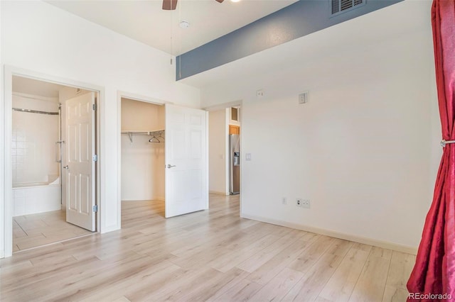 unfurnished bedroom with visible vents, connected bathroom, stainless steel fridge with ice dispenser, a spacious closet, and light wood-style floors