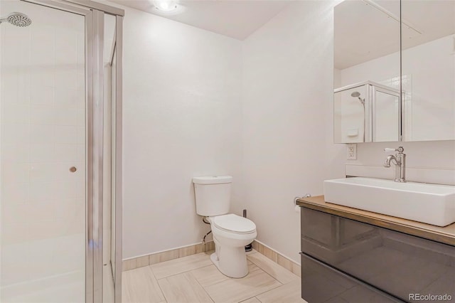 bathroom with toilet, a shower stall, baseboards, and vanity