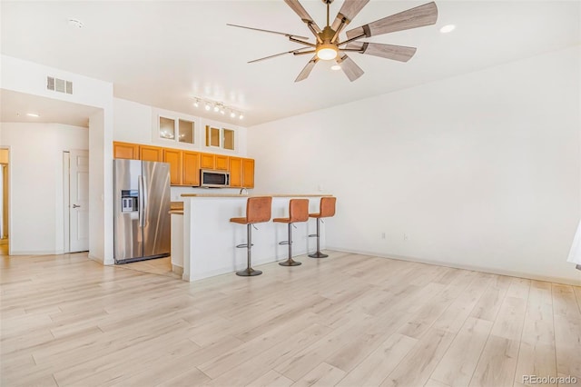 kitchen with a breakfast bar, visible vents, a ceiling fan, appliances with stainless steel finishes, and light wood finished floors