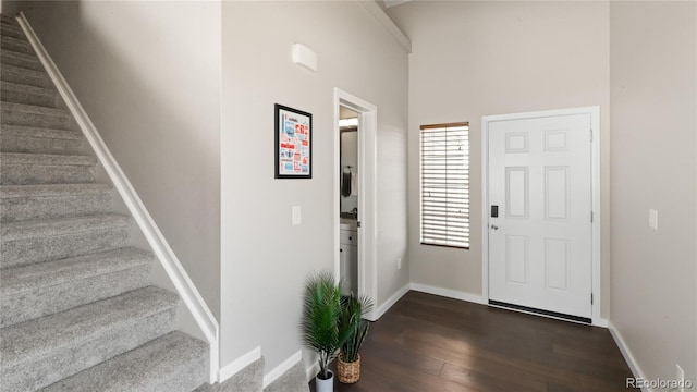 entryway featuring stairway, dark wood-type flooring, and baseboards