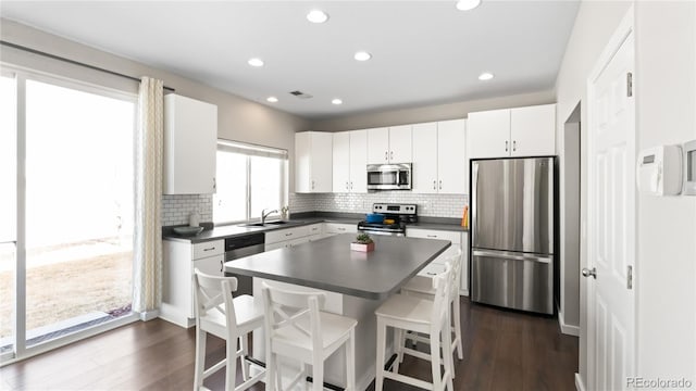 kitchen featuring a kitchen bar, dark countertops, dark wood-type flooring, and appliances with stainless steel finishes