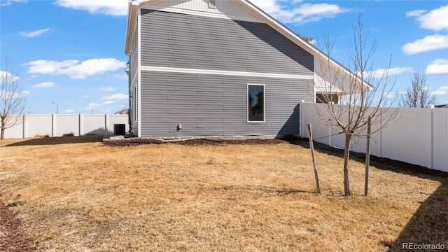 view of side of property with a yard, central AC unit, and a fenced backyard