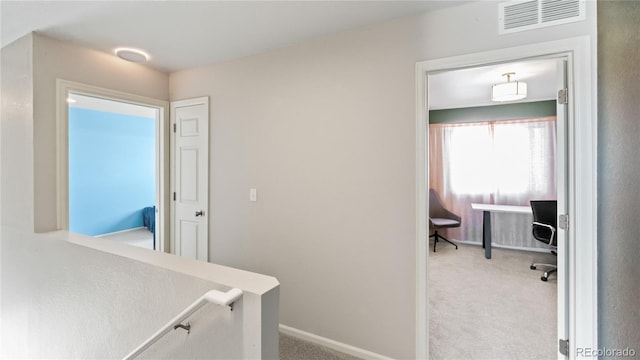 corridor with carpet, visible vents, and baseboards