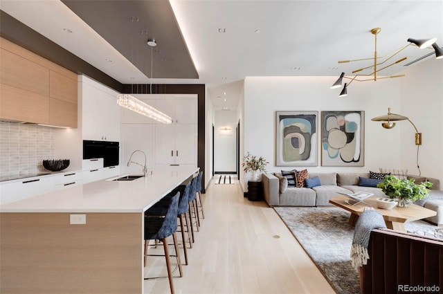 kitchen with pendant lighting, tasteful backsplash, sink, a breakfast bar area, and white cabinets