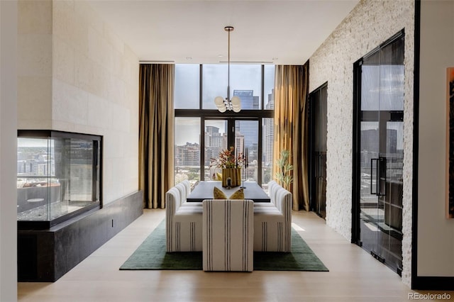 dining space with floor to ceiling windows, a chandelier, and light hardwood / wood-style floors