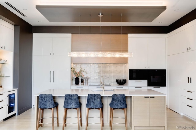 kitchen with a kitchen island with sink, sink, wine cooler, and a kitchen breakfast bar