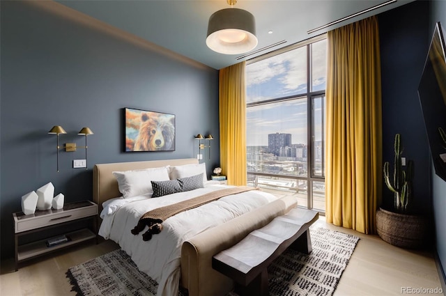 bedroom featuring expansive windows, access to exterior, and light wood-type flooring