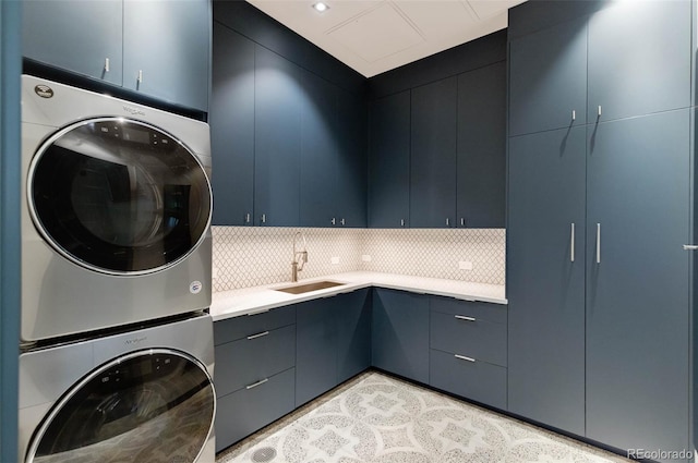 laundry room featuring cabinets, stacked washing maching and dryer, and sink