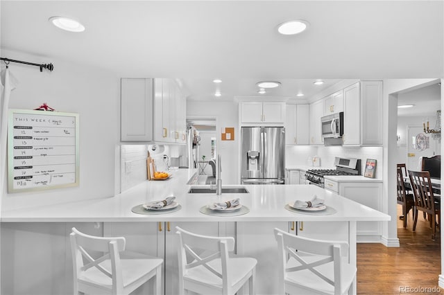 kitchen with stainless steel appliances, a sink, a peninsula, light countertops, and backsplash