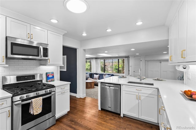 kitchen with stainless steel appliances, a sink, light countertops, white cabinetry, and a peninsula