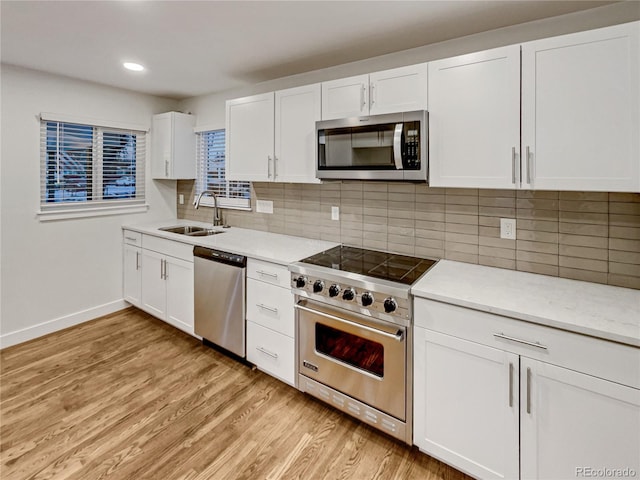 kitchen featuring white cabinets, sink, light wood-type flooring, and stainless steel appliances