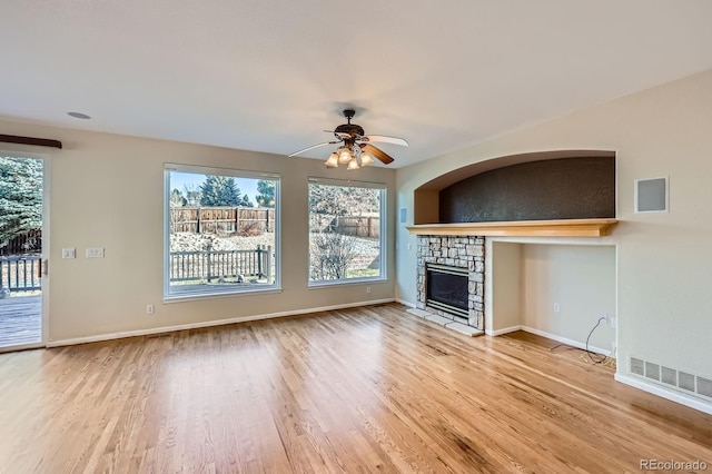 unfurnished living room with wood finished floors, a fireplace, visible vents, and ceiling fan