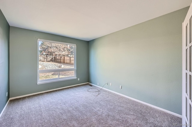 carpeted empty room featuring baseboards