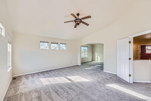 carpeted empty room with visible vents, baseboards, high vaulted ceiling, arched walkways, and ceiling fan