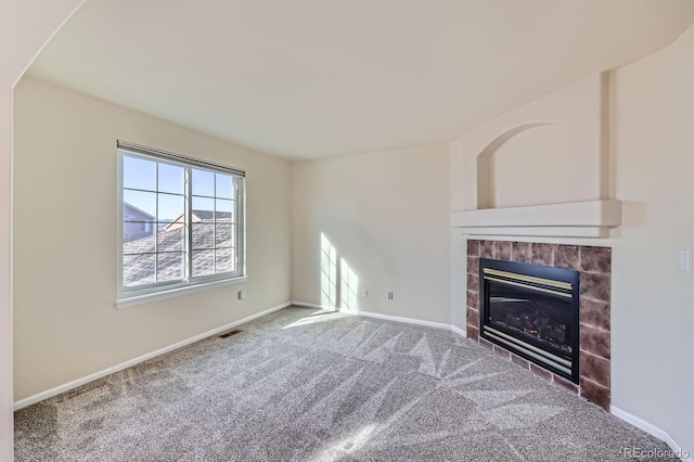 unfurnished living room featuring a tiled fireplace, carpet, visible vents, and baseboards