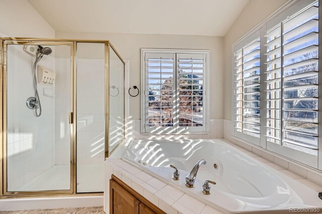 bathroom featuring lofted ceiling, a tub with jets, and a stall shower