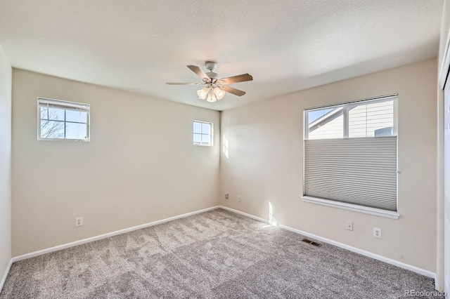 carpeted spare room with visible vents, a textured ceiling, baseboards, and a ceiling fan