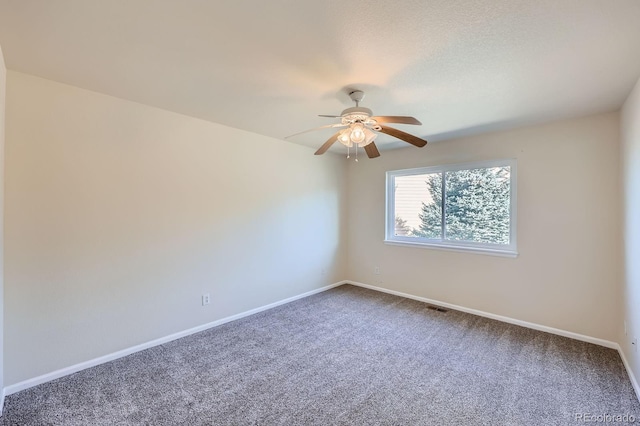 carpeted spare room featuring visible vents, baseboards, and ceiling fan