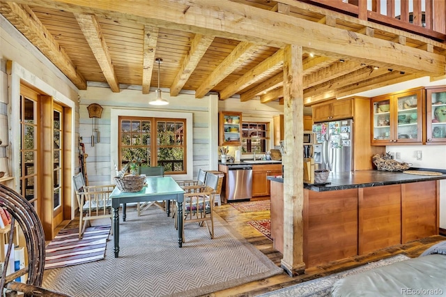 kitchen featuring beamed ceiling, wooden walls, wood ceiling, hanging light fixtures, and appliances with stainless steel finishes