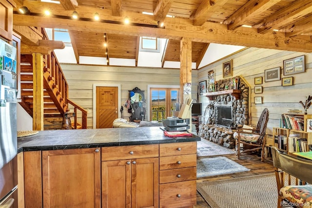 kitchen featuring a fireplace, wooden ceiling, wood-type flooring, wood walls, and vaulted ceiling with beams