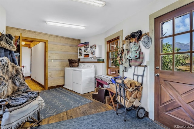 laundry area with hardwood / wood-style floors, independent washer and dryer, and wooden walls