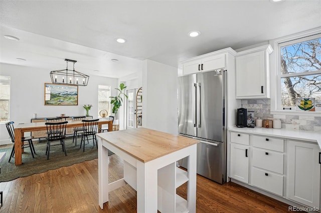 kitchen with tasteful backsplash, recessed lighting, high end refrigerator, light countertops, and dark wood-style flooring