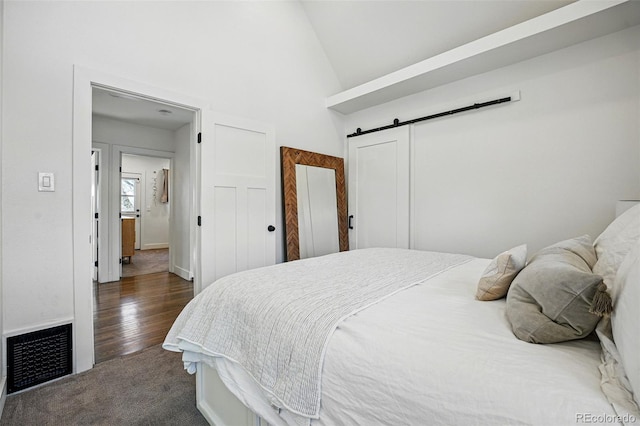 bedroom with high vaulted ceiling, dark colored carpet, visible vents, and a barn door