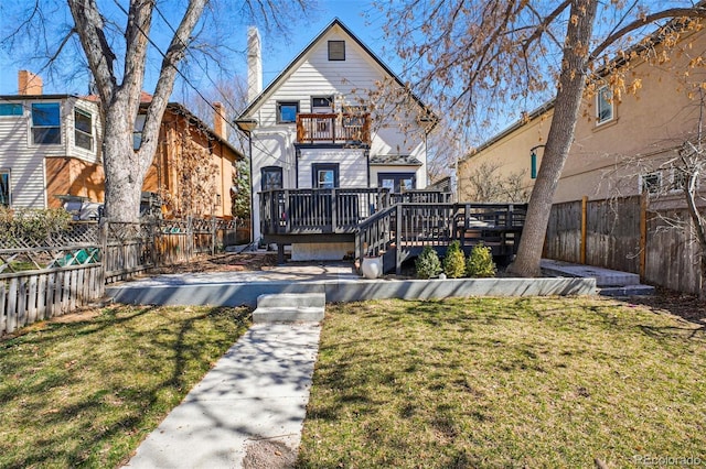 rear view of property with a fenced backyard, a deck, and a lawn