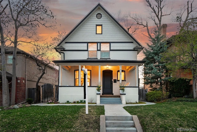 view of front of home with a porch, a front yard, and fence