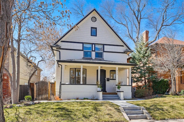 american foursquare style home featuring a porch, fence, a front lawn, and a gate